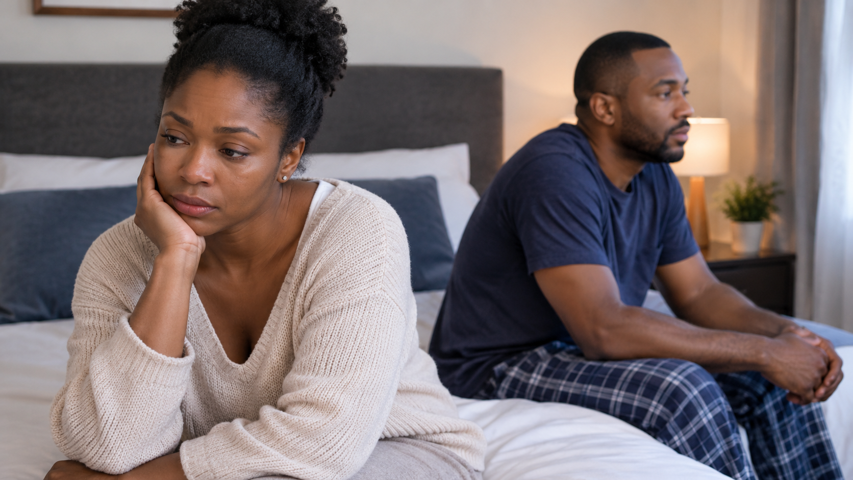 Sad woman sitting apart from her emotionally distant partner on their bed.